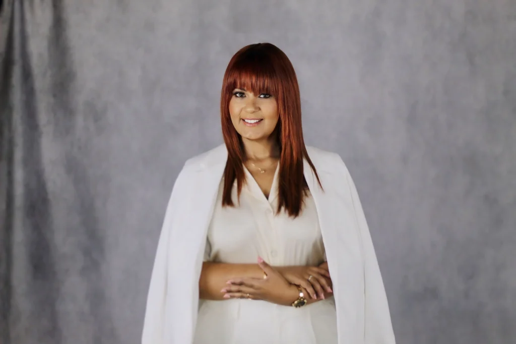 Melissa-doula in white outfit, neutral background.